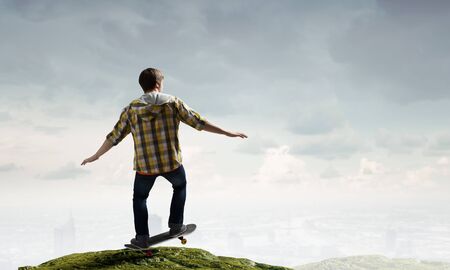 Active guy riding skateboard on rock edgeの写真素材