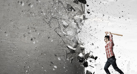 Furious hipster guy breaking wall with baseball batの写真素材