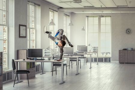 Youngh cheerful businessman dancing in office. Mixed mediaの写真素材