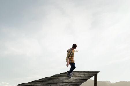 Active guy riding skateboard on wooden pierの写真素材