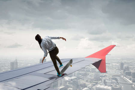 Active girl riding skateboard on airplane wing