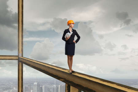 Young woman architect in hardhat holding project in hand