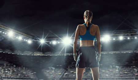 Young pretty boxer woman standing in lights of sport arenaの写真素材