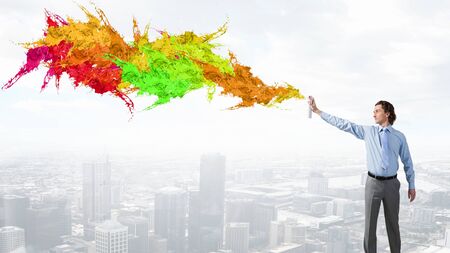 Young businessman against cityscape spraying paint from aerosol canの写真素材