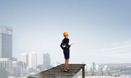 Young woman architect in hardhat holding project in handの写真素材