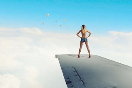 Traveler woman in bikini and shorts on airplane wingの写真素材