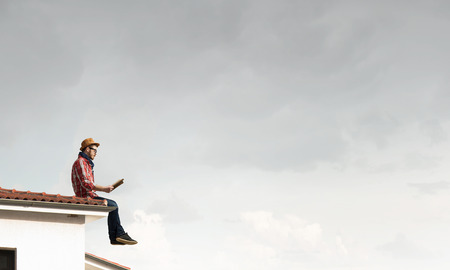 Hipster guy with book on building roofの写真素材