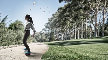 Active girl riding skateboard on road in park