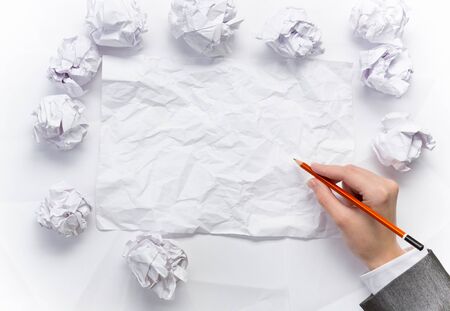 Hand of businesswoman writing on blank crumpled sheet of paperの写真素材