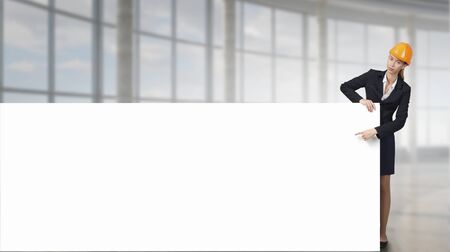 Attractive woman builder demonstrating white blank banner. Mixed mediaの写真素材