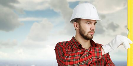 Engineer man in helmet outdoor using level