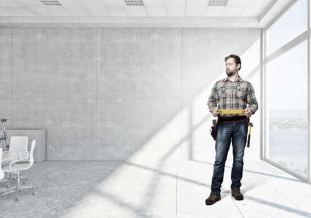 Builder man in checked shirt with tool belt on waist. Mixed mediaの写真素材