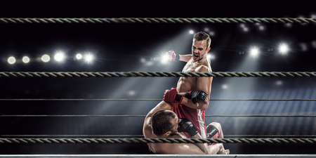 Two professional boxers fighting on arena in spotlightsの写真素材