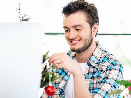 Portrait of young office worker decorating Christmas treeの写真素材