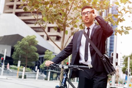 Young businessman wearing suit with bike outdoorsの写真素材