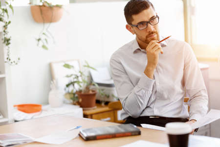 Young businessman sitting at desk and working in office
