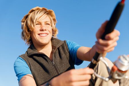 Teenage boy fishing with rod at seaの写真素材