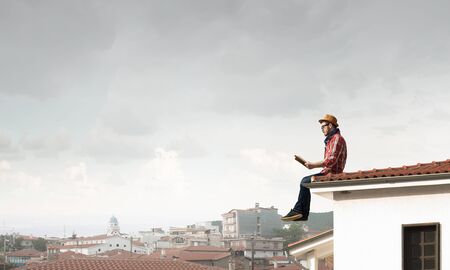 Hipster guy with book on building roofの写真素材