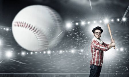 Hipster guy with baseball bat in lights of stageの写真素材