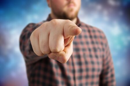 Young man in checked shirt showing his index finger towards cameraの写真素材