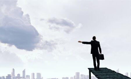 Back view of businessman standing on bay and viewing cityの写真素材