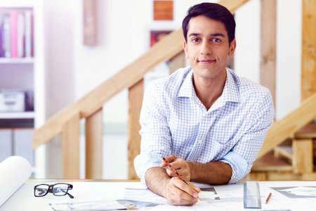 Young man in casual clothes in an office with draftsの写真素材