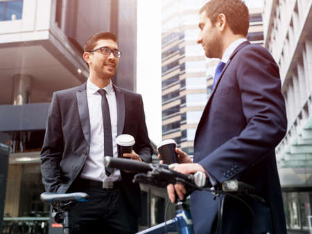 Two businessmen talking outdoors while taking coffee breakの写真素材