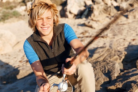 Teenage boy fishing with rod at seaの写真素材