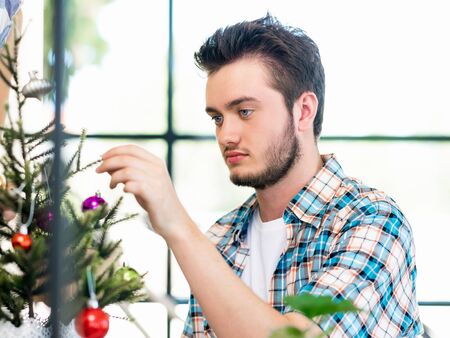 Portrait of young office worker decorating Christmas treeの写真素材