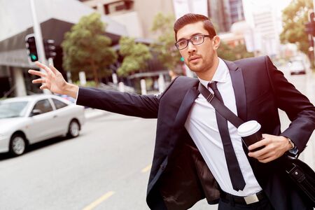 Young businessman wearing suit catching taxiの写真素材