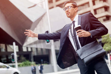 Young businessman wearing suit catching taxiの写真素材