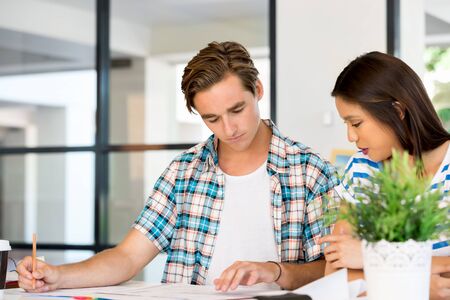 Two young office workers working together at the desk