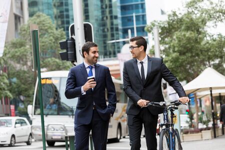 Young businessman with bike talking to his colleagueの写真素材