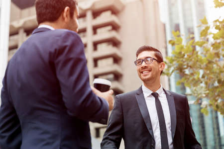 Two businessmen talking outdoors while taking coffee breakの写真素材