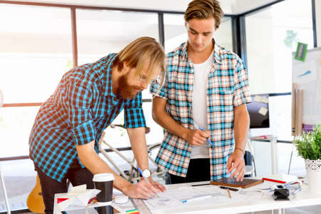 Two young office workers working together at the deskの写真素材
