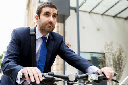 Young businessman wearing suit with bike outdoorsの写真素材