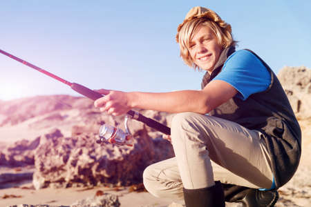 Teenage boy fishing with rod at sea