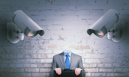 Unrecognizable businessman in room standing under security camera