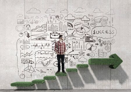 Young man in glasses and checked shirt and sketches on wallの写真素材