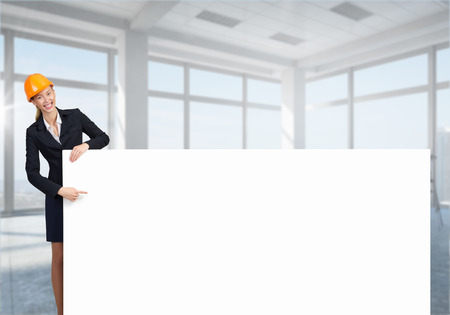 Attractive woman builder demonstrating white blank banner. Mixed mediaの写真素材