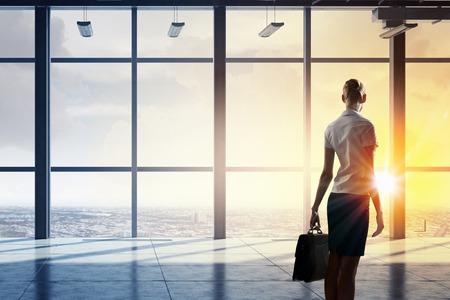 Back view of businesswoman against panoramic office window. Mixed mediaの写真素材