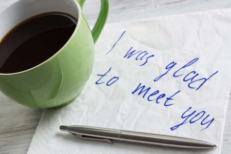 Romantic message written on napkin and cup of coffee on wooden table