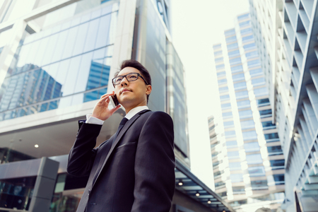 Businessman in city holding his mobileの写真素材