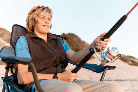 Teenage boy fishing with rod at seaの写真素材