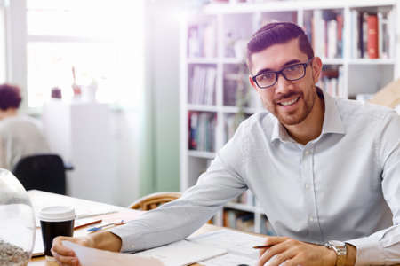 Young businessman sitting at desk and working in office