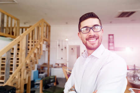 Young businessman standing in office and smiling into the cameraの写真素材