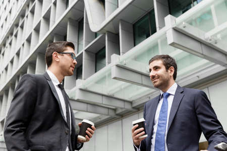 Two businessmen talking outdoors while taking coffee breakの写真素材