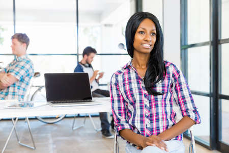 Portrait of beautiful smiling afro-american office worker sitting in office