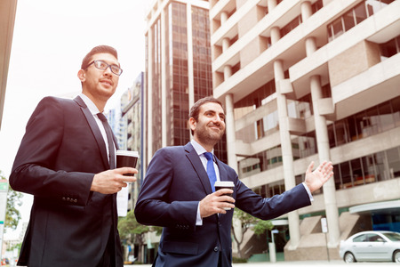 Two young businessmen in suits catching taxiの写真素材