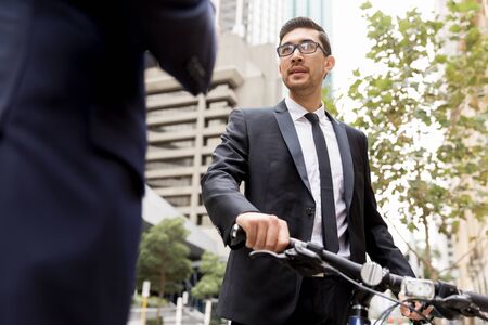 Young businessman with bike talking to his colleagueの写真素材